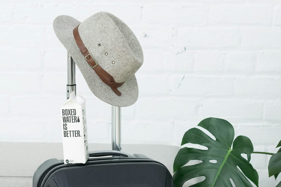 A hat and Boxed Water carton sit on a suitcase